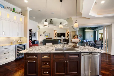 a large kitchen with stainless steel appliances kitchen island granite countertop a sink a stove and a wooden floors