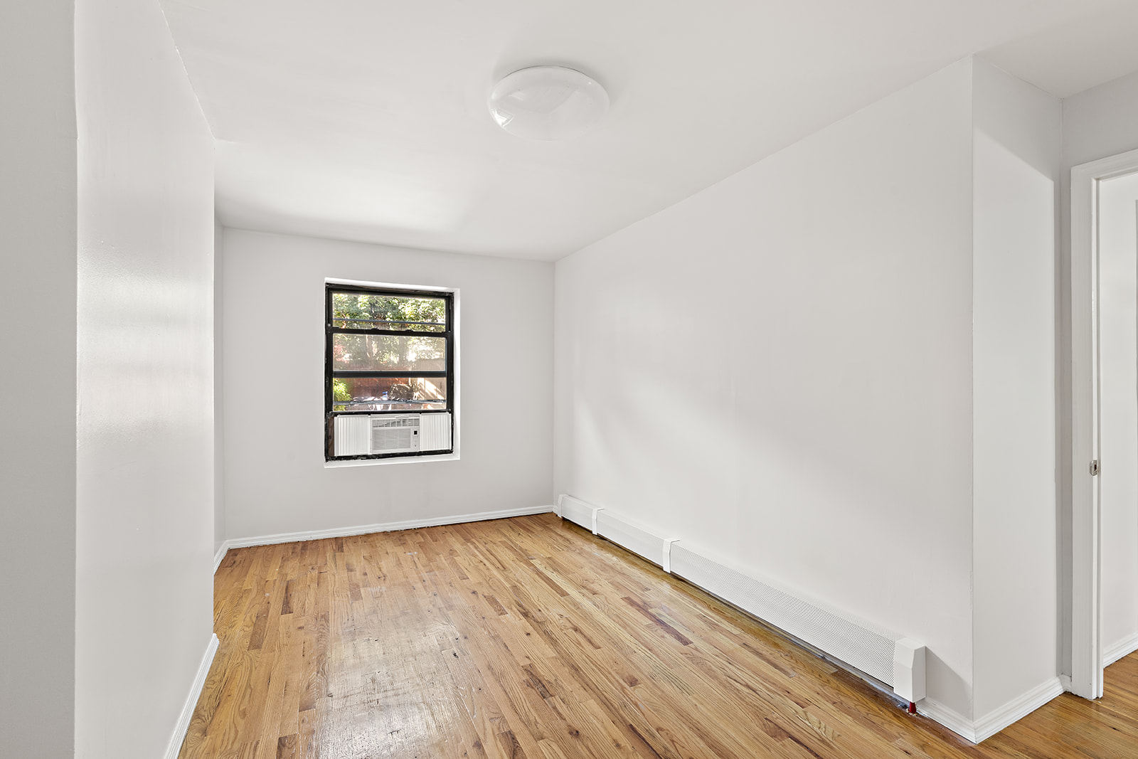 383 Bainbridge Street, Unit 1 Brooklyn, NY 11233 - Photo 6 of 14 an empty room with wooden floor and windows
