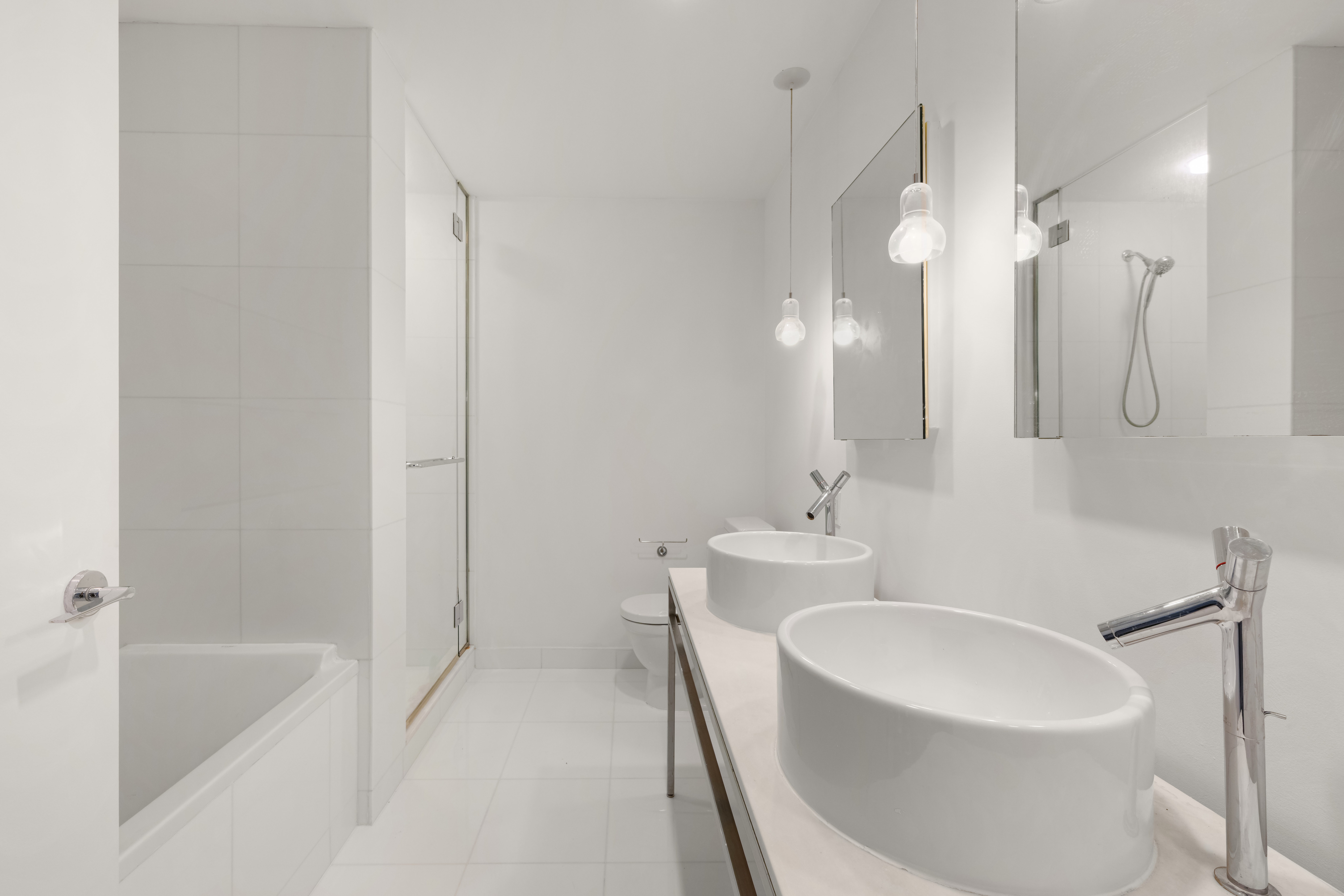 15 Broad Street, Unit 710 Manhattan, NY 10005 - Photo 5 of 11 a bathroom with a bathtub a sink a toilet and a mirror
