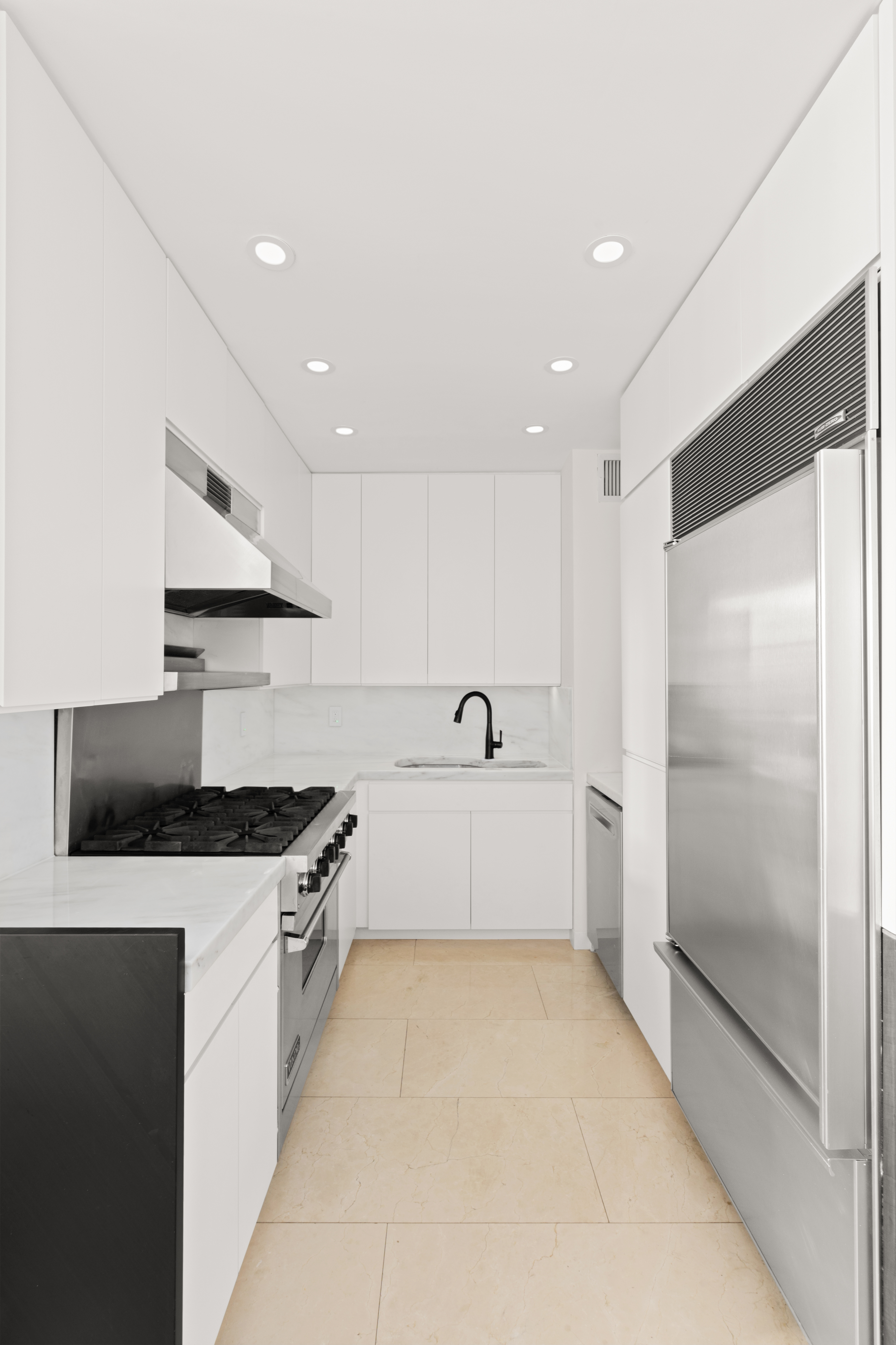 425 Park Avenue South, Unit 20B Manhattan, NY 10016 - Photo 5 of 8 a large kitchen with stainless steel appliances a white stove top oven and white cabinets