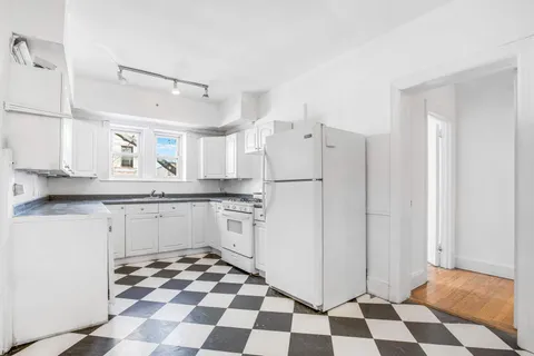 a kitchen with a checkered floor and white cabinets