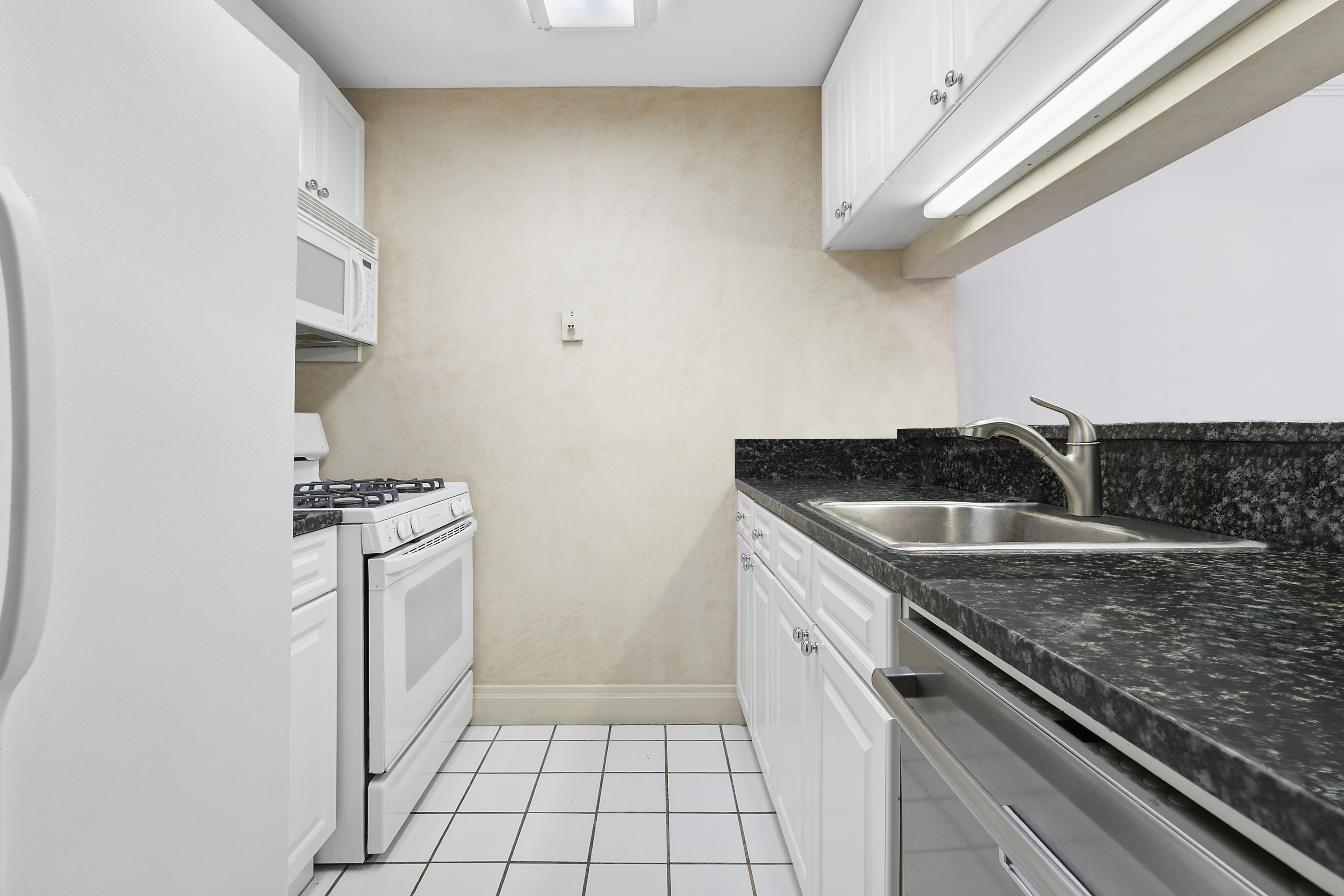 404 East 76th Street, Unit 4H Manhattan, NY 10021 - Photo 5 of 10 a kitchen with a sink cabinets and stainless steel appliances