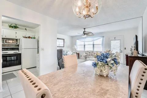 a very nice looking dining room with kitchen island stainless steel appliances furniture a fireplace and a chandelier