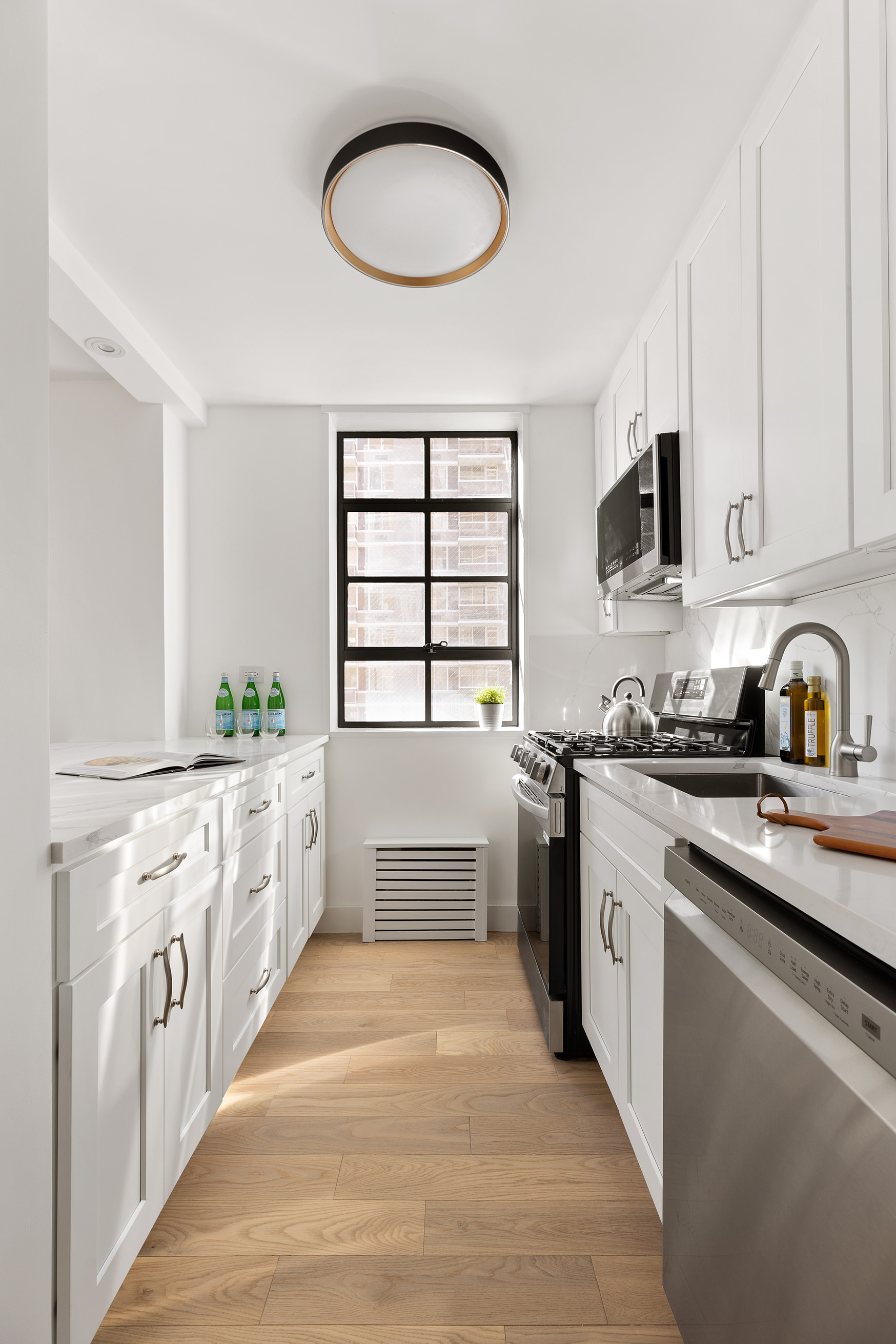 200 East 90th Street, Unit 12F Manhattan, NY 10128 - Photo 2 of 13 a kitchen with stainless steel appliances a white stove top oven a sink with white cabinets and a large window