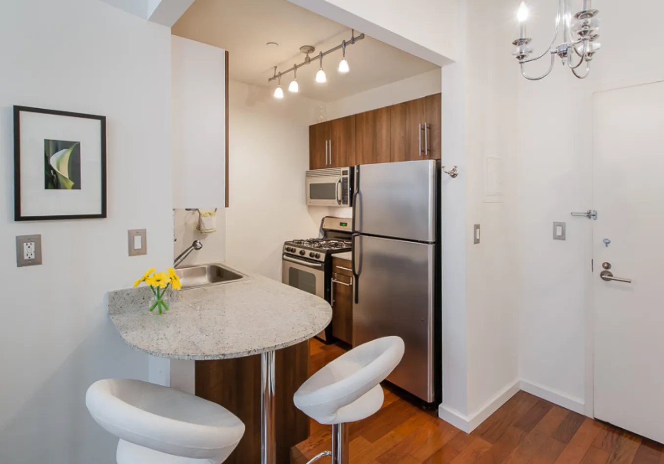 a kitchen with stainless steel appliances a refrigerator a sink a dining table and chairs