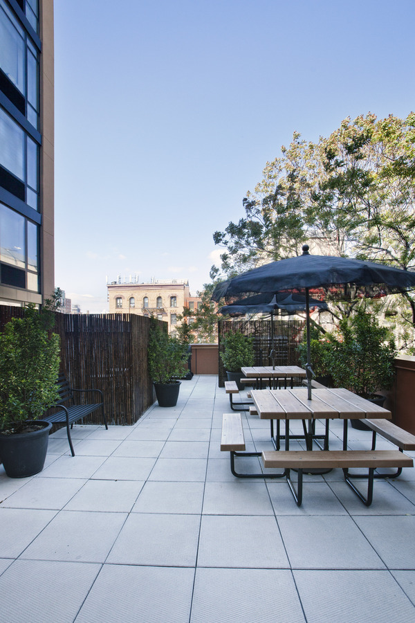 1595 Lexington Avenue, Unit 6E Manhattan, NY 10029 - Photo 11 of 13 a view of a patio with a table and chairs under an umbrella with a fire pit
