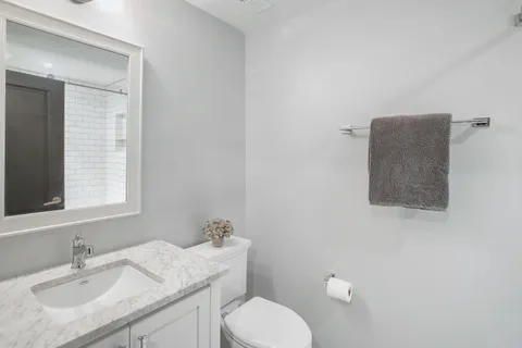 a bathroom with a granite countertop toilet sink and mirror