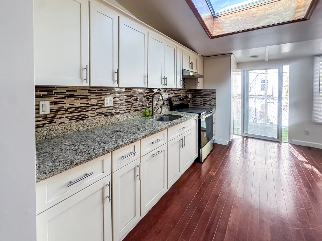 a kitchen with granite countertop wooden floors and white cabinets