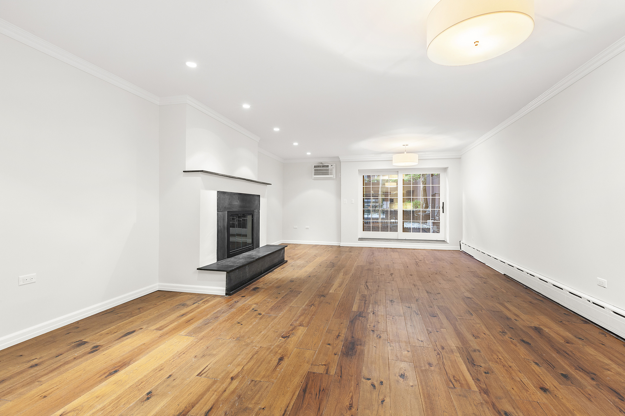 522 East 82nd Street, Unit 1 Manhattan, NY 10028 - Photo 3 of 16 an empty room with wooden floor and fireplace