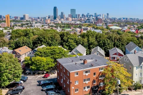 an aerial view of residential houses with outdoor space and trees