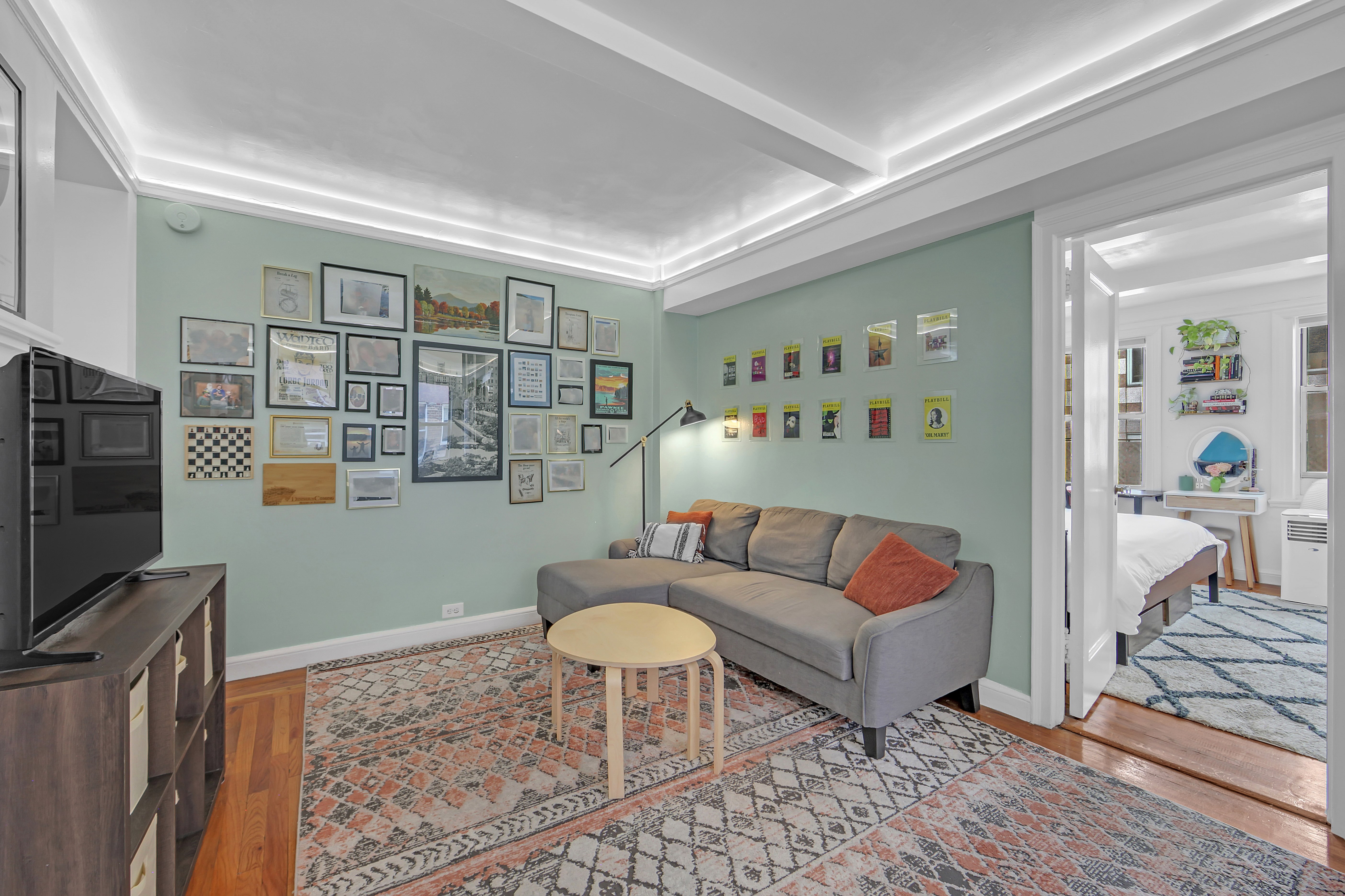 333 East 43rd Street, Unit 909 Manhattan, NY 10017 - Photo 5 of 22 a living room with furniture a flat screen tv and a table