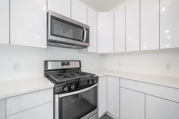 a kitchen with stainless steel appliances granite countertop white cabinets and a stove top oven