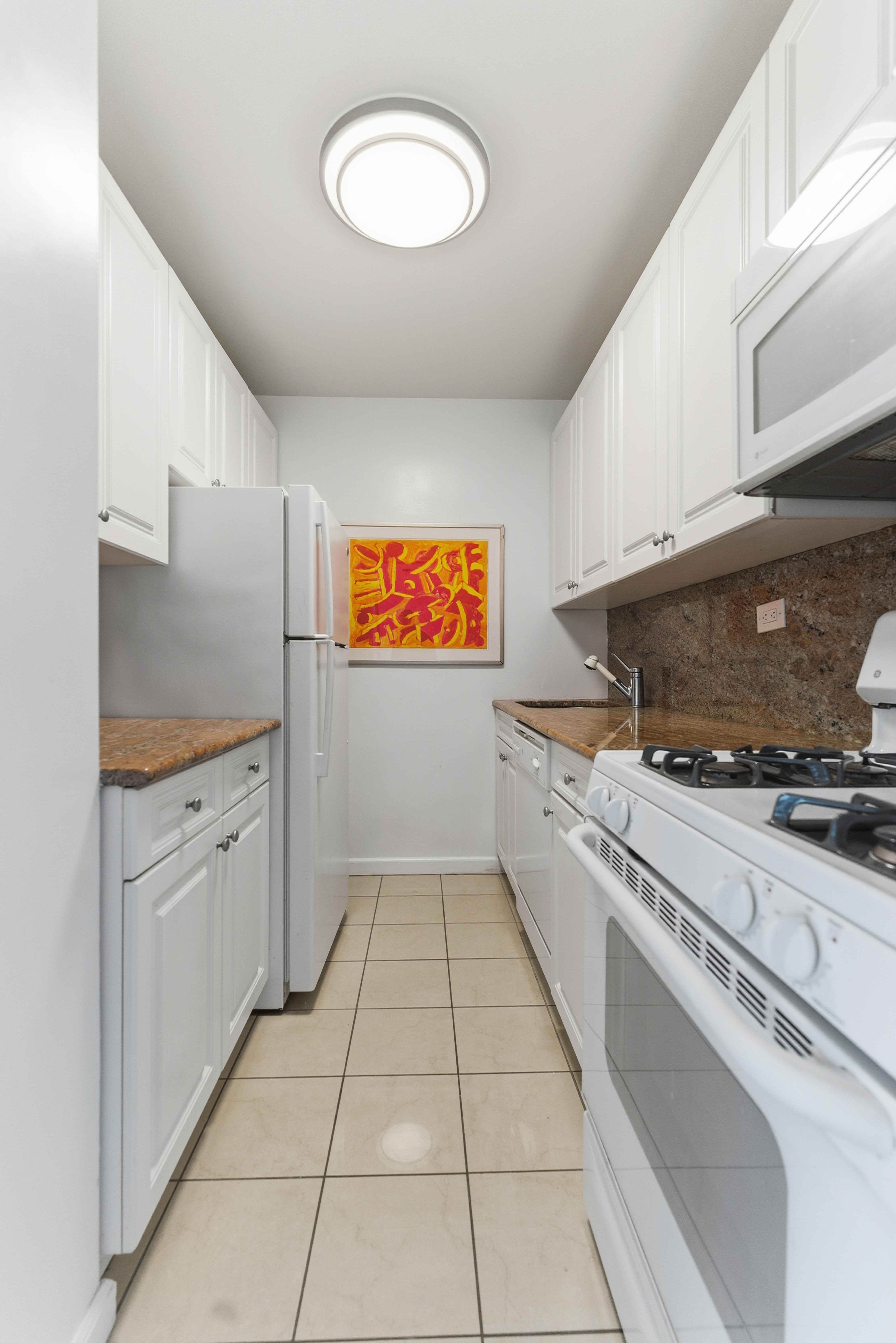 140 West End Avenue, Unit 6D Manhattan, NY 10023 - Photo 9 of 19 a kitchen with granite countertop white cabinets and white appliances