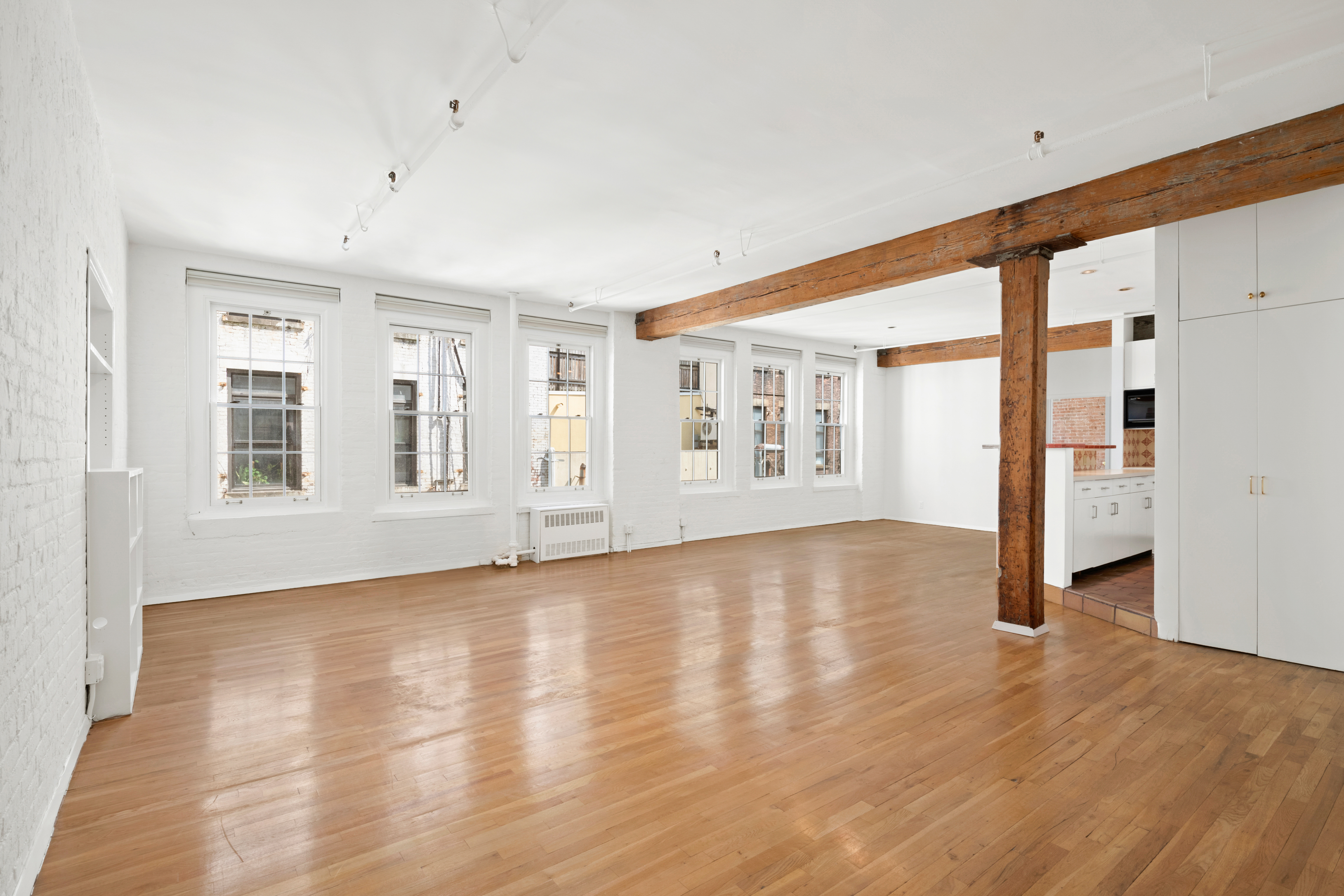 140 Thompson, Unit 4A Manhattan, NY 10012 - Photo 2 of 13 an empty room with wooden floor and windows