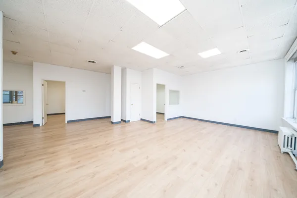 a view of an empty room with wooden floor and closet