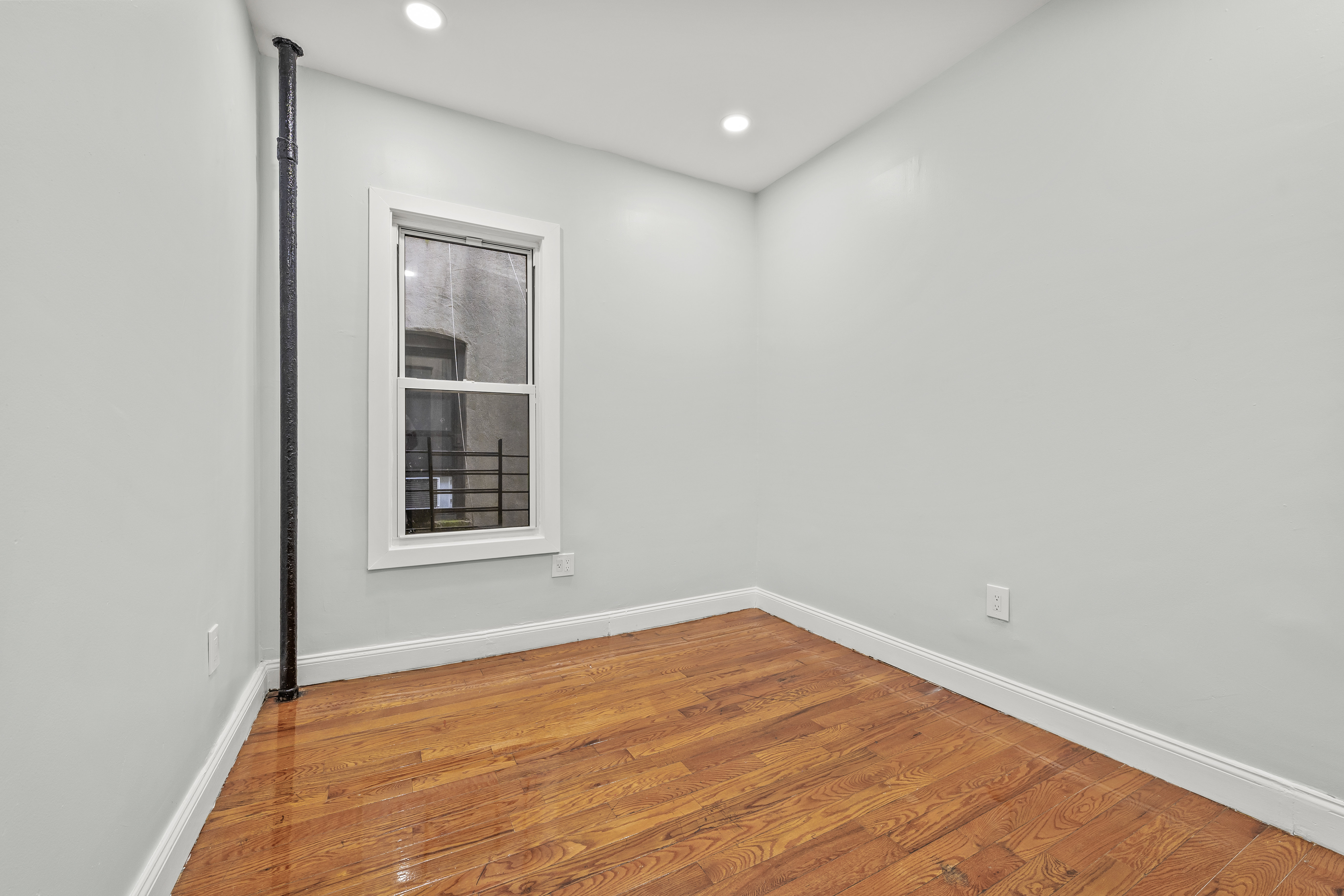2023 Hughes Avenue Bronx, NY 10457 - Photo 10 of 63 a view of an empty room with wooden floor and a window