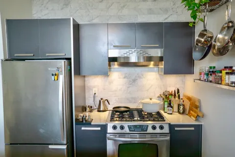 a kitchen with stainless steel appliances a refrigerator a sink a stove and a refrigerator