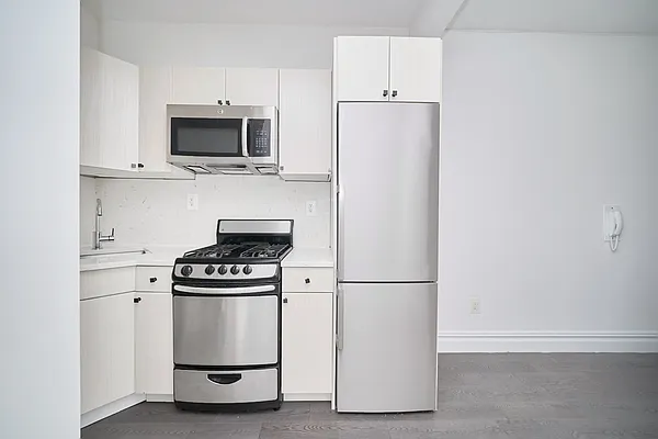 20 Avenue A, Unit 5E Manhattan, NY 10009 - Photo 3 of 7 a kitchen with white cabinets and stainless steel appliances