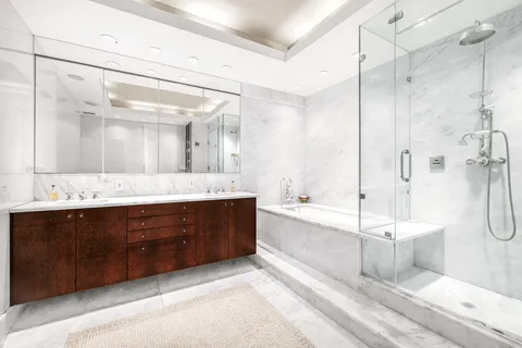 a spacious bathroom with a bathtub shower sink mirror and toilet