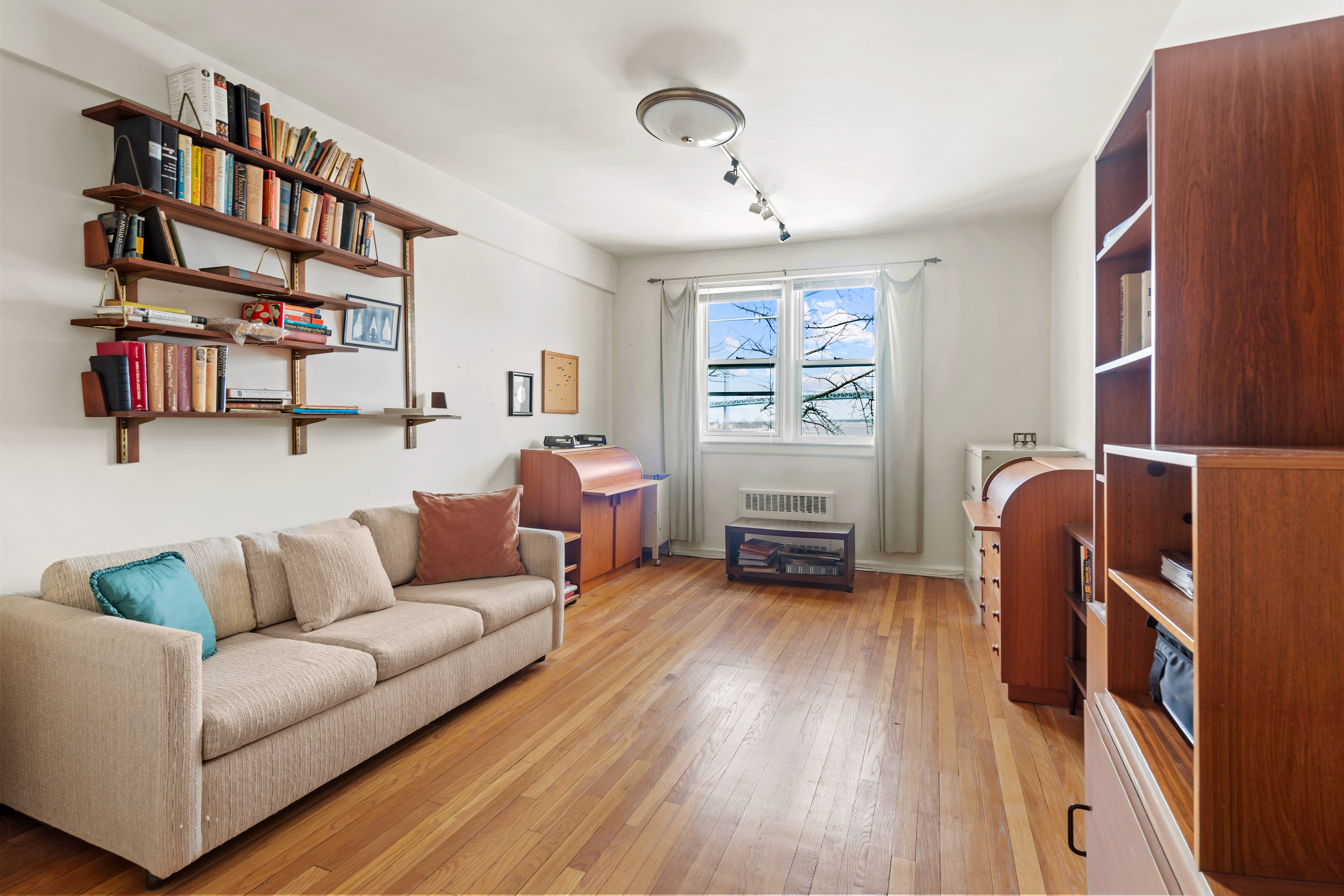 162-01 Powells Cove Boulevard, Unit 4R Queens, NY 11357 - Photo 7 of 12 a living room with furniture and a book shelf
