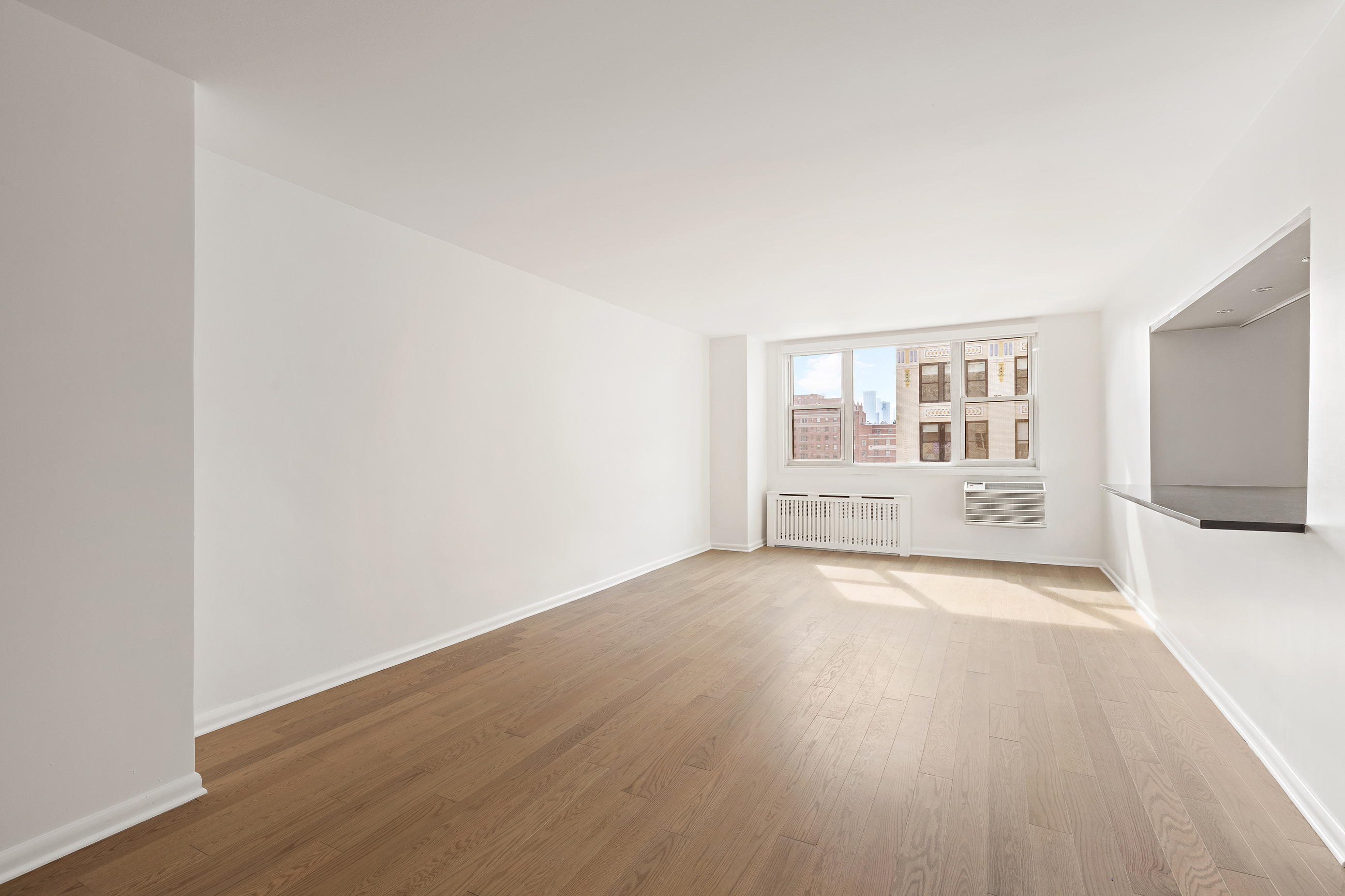 77 7th Avenue, Unit 12P Manhattan, NY 10011 - Photo 2 of 15 an empty room with wooden floor and windows