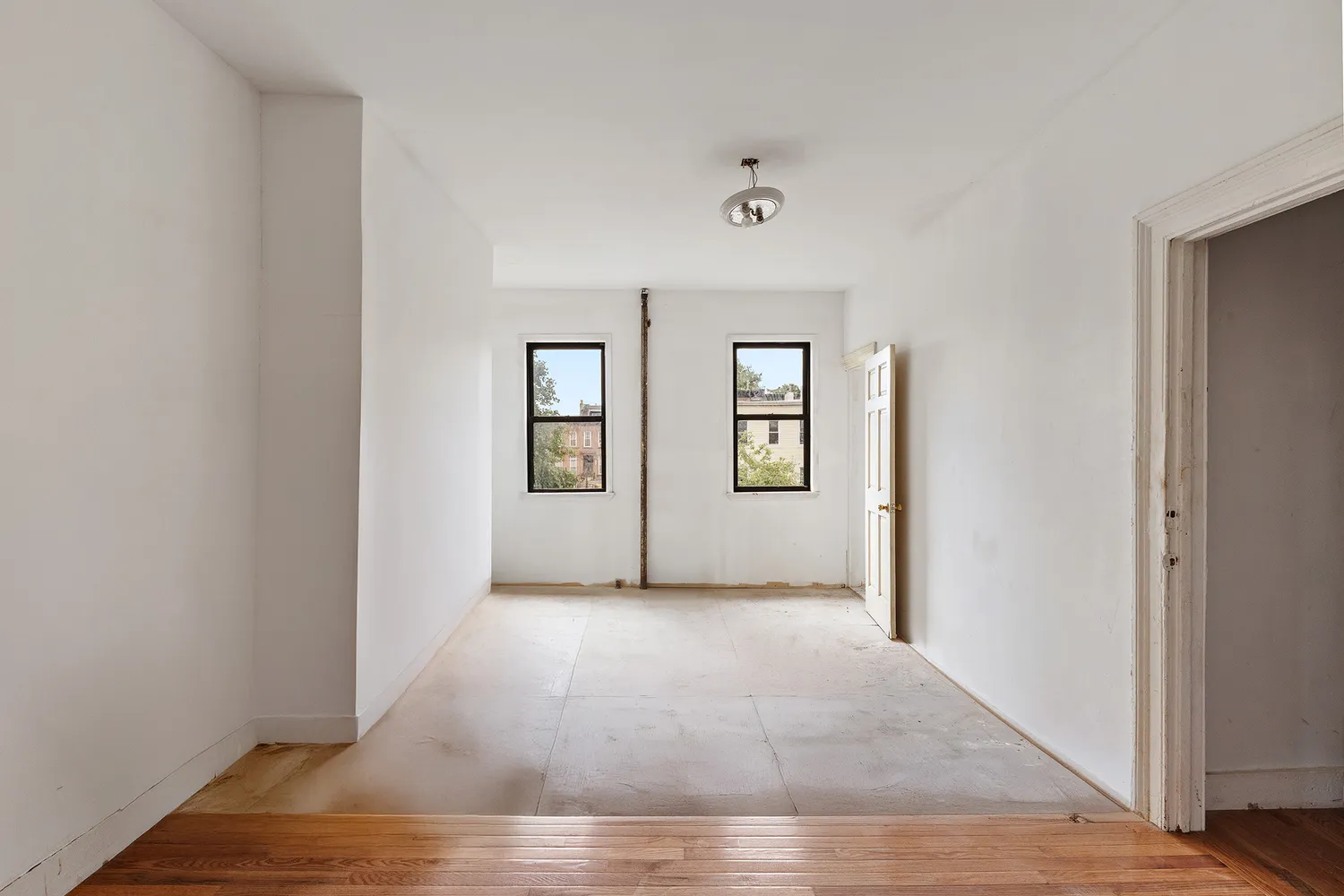 an empty room with wooden floor and windows
