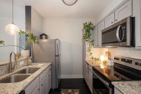 a kitchen with stainless steel appliances granite countertop a sink a stove and a microwave