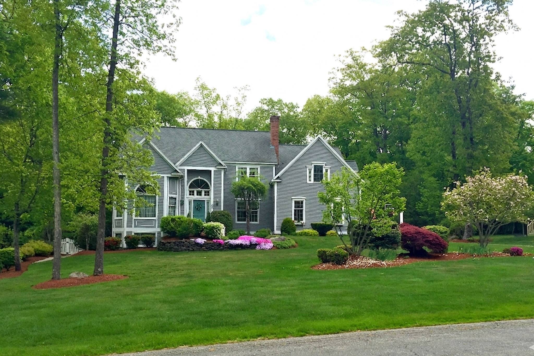 a front view of a house with a garden and trees