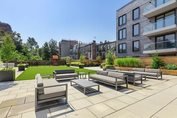 a view of a patio with couches and a fire pit and wooden fence