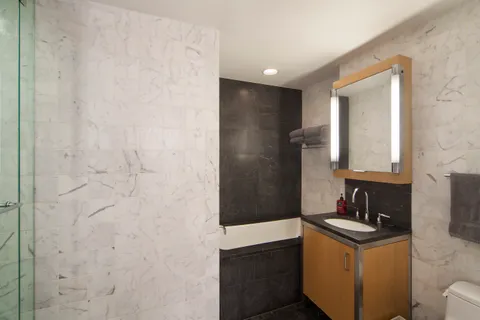 a bathroom with a granite countertop sink a mirror and shower