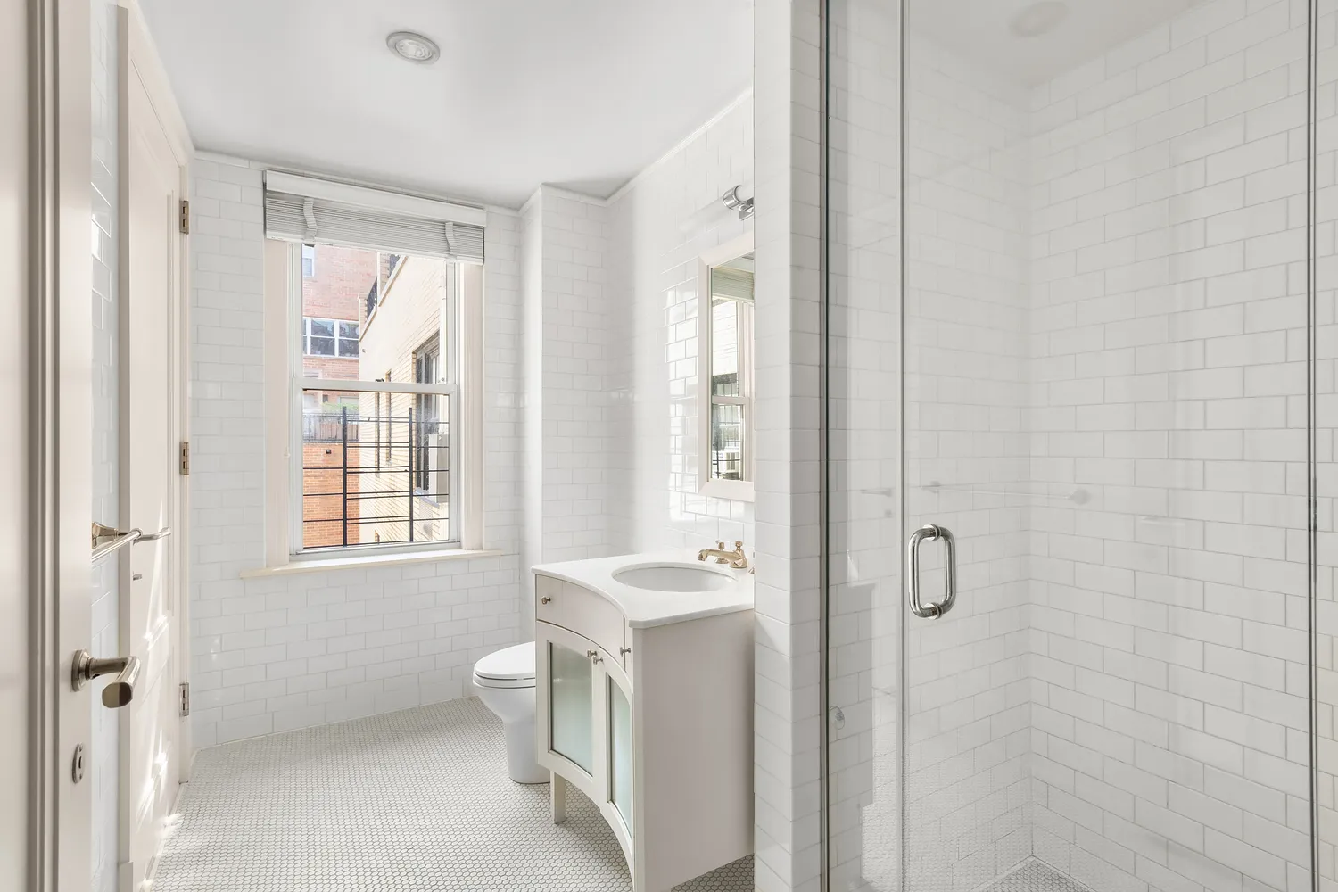 a bathroom with a granite countertop toilet a sink a mirror a window and a shower
