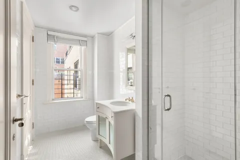 a bathroom with a granite countertop toilet a sink a mirror a window and a shower