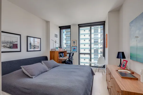 a bedroom with a bed a dresser and a large window