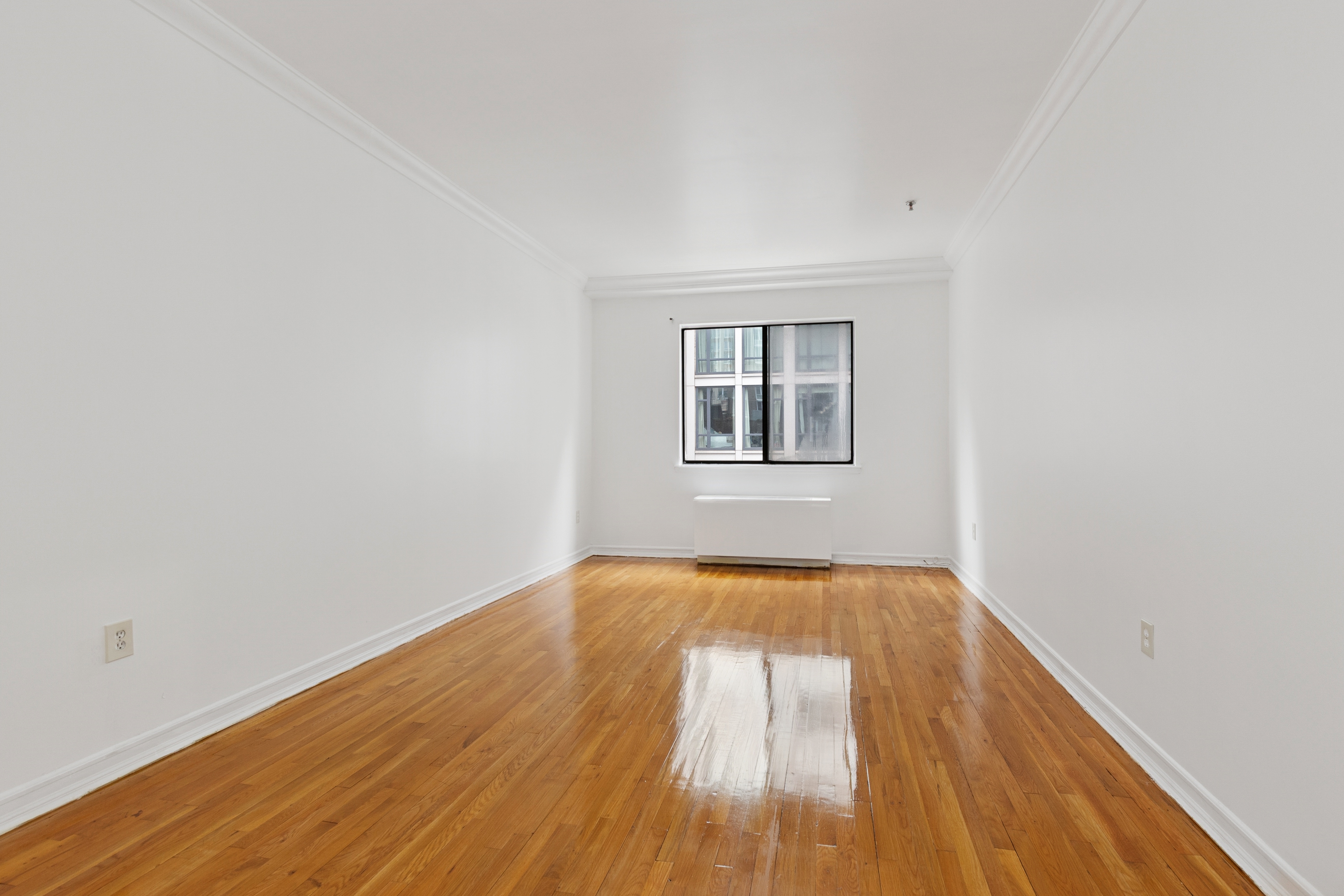 136-140 West 23rd Street, Unit 4CC Manhattan, NY 10011 - Photo 9 of 13 an empty room with wooden floor and windows