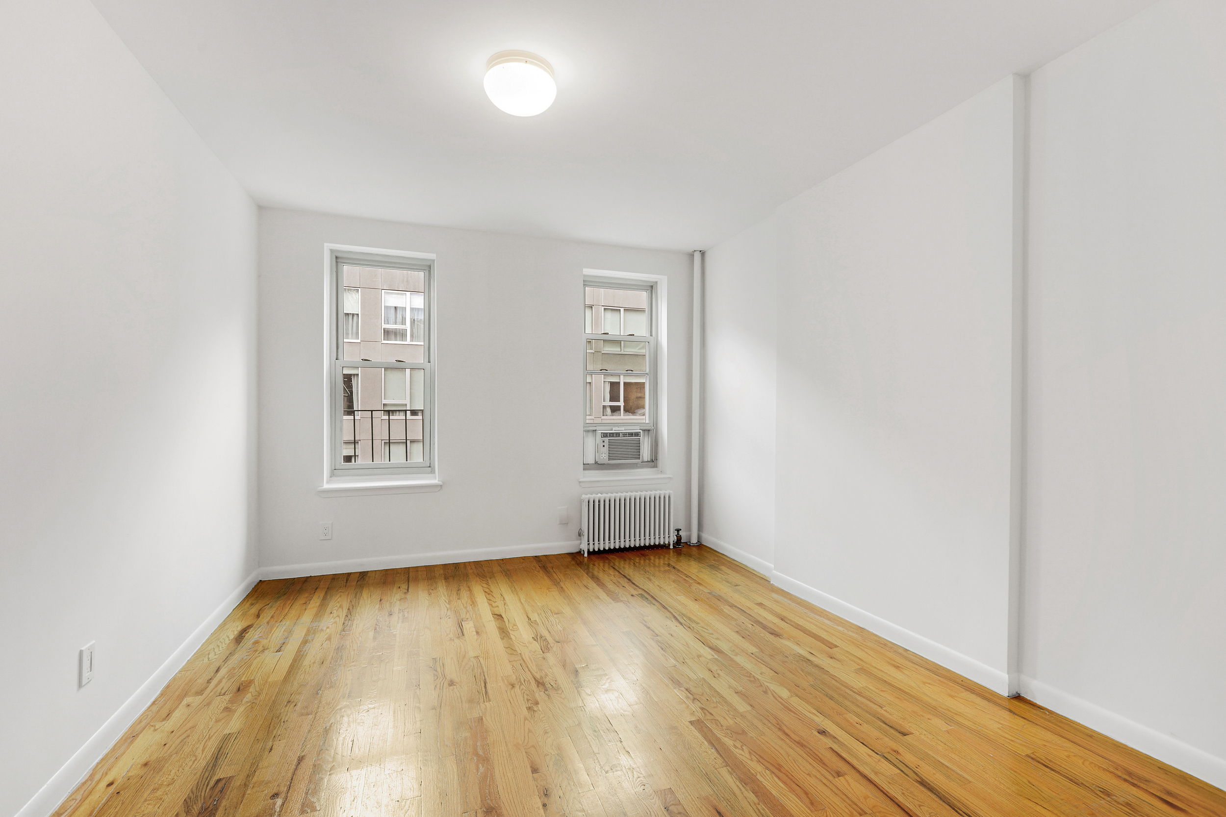 323 West 43rd Street, Unit 4R Manhattan, NY 10036 - Photo 2 of 14 an empty room with wooden floor and windows