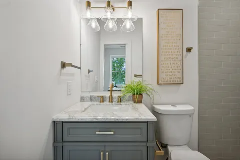 a bathroom with a granite countertop toilet a sink and a mirror