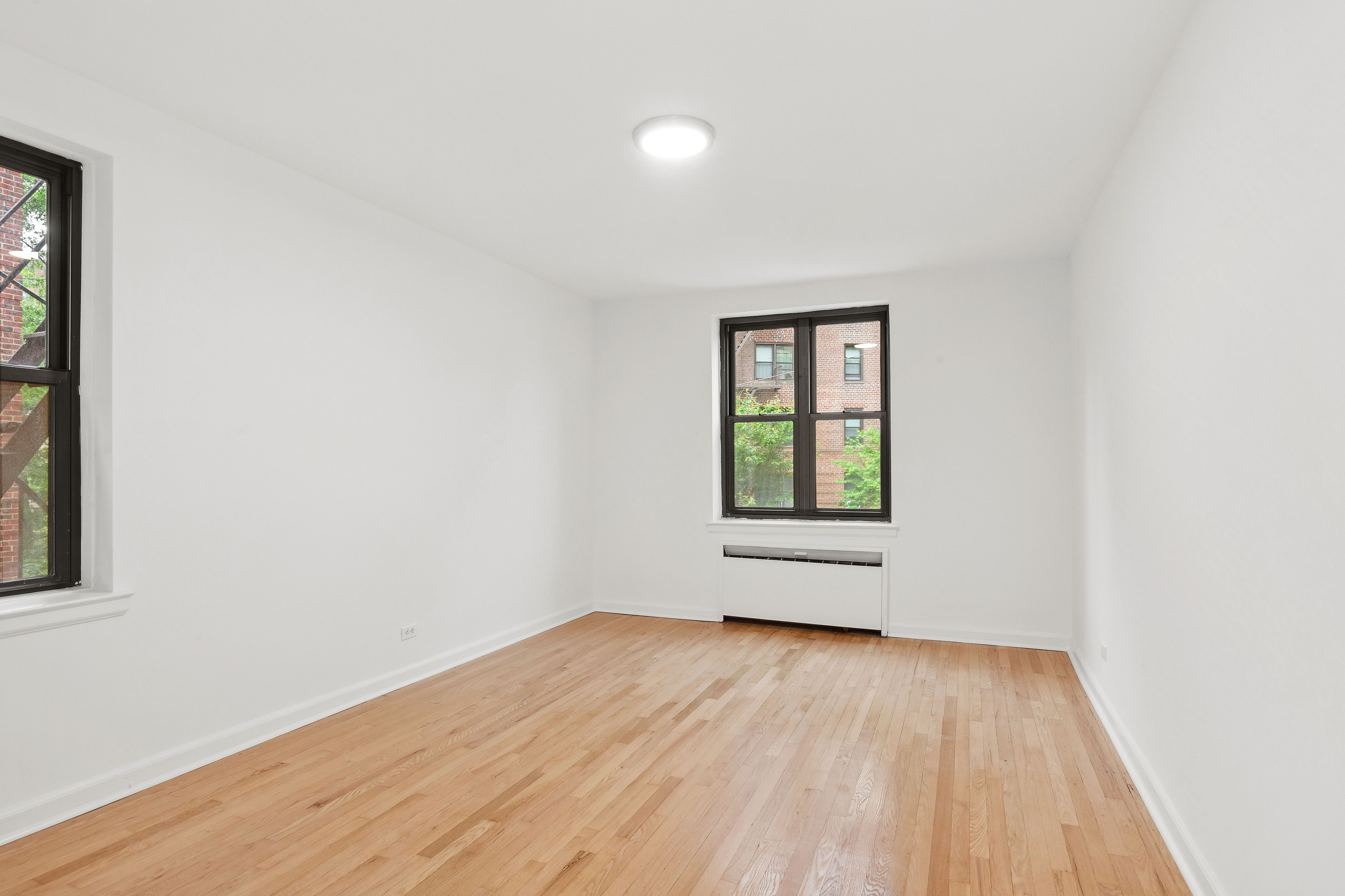 445 West 240th Street, Unit 3A Bronx, NY 10463 - Photo 3 of 8 an empty room with wooden floor and windows