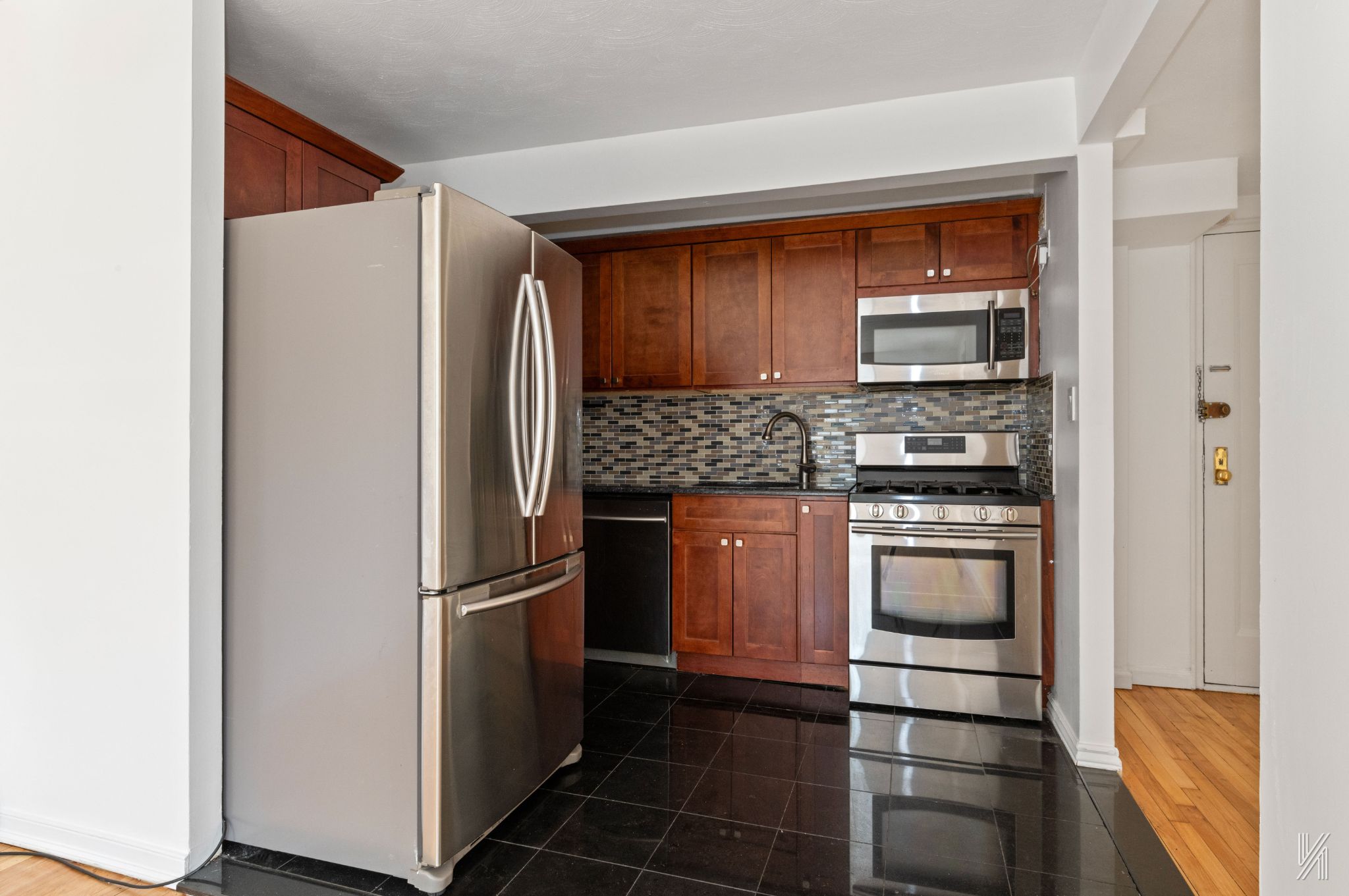 87-10 34th Avenue, Unit 1F Queens, NY 11372 - Photo 8 of 16 a kitchen with stainless steel appliances granite countertop a refrigerator and a sink