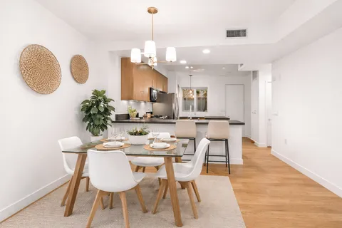 a dining room with wooden floor a chandelier a wooden table and chairs
