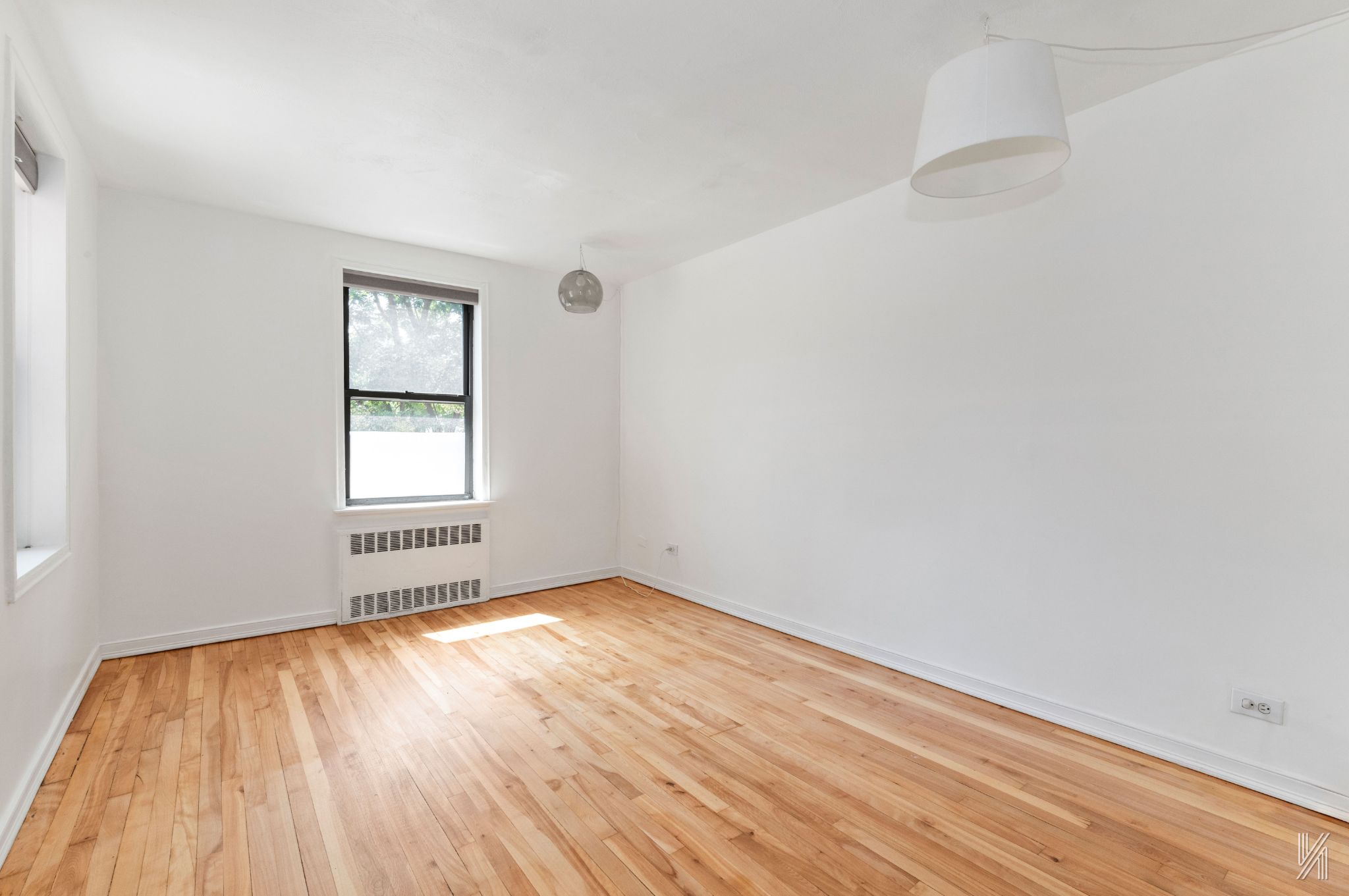 87-10 34th Avenue, Unit 1F Queens, NY 11372 - Photo 2 of 16 an empty room with wooden floor and windows