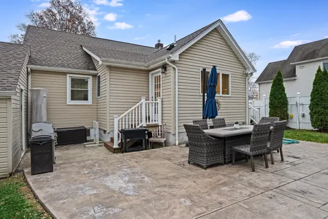 a backyard of a house with dining table and chairs