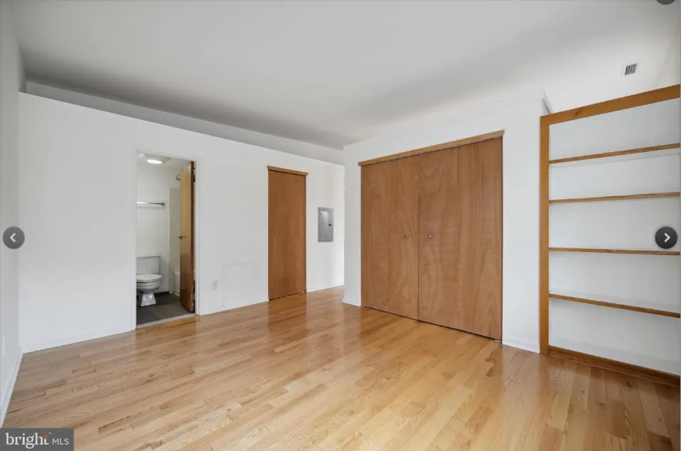 a view of an empty room with wooden floor and closet