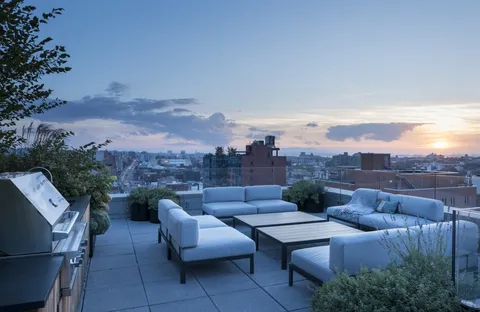 a view of roof deck with couches and potted plants