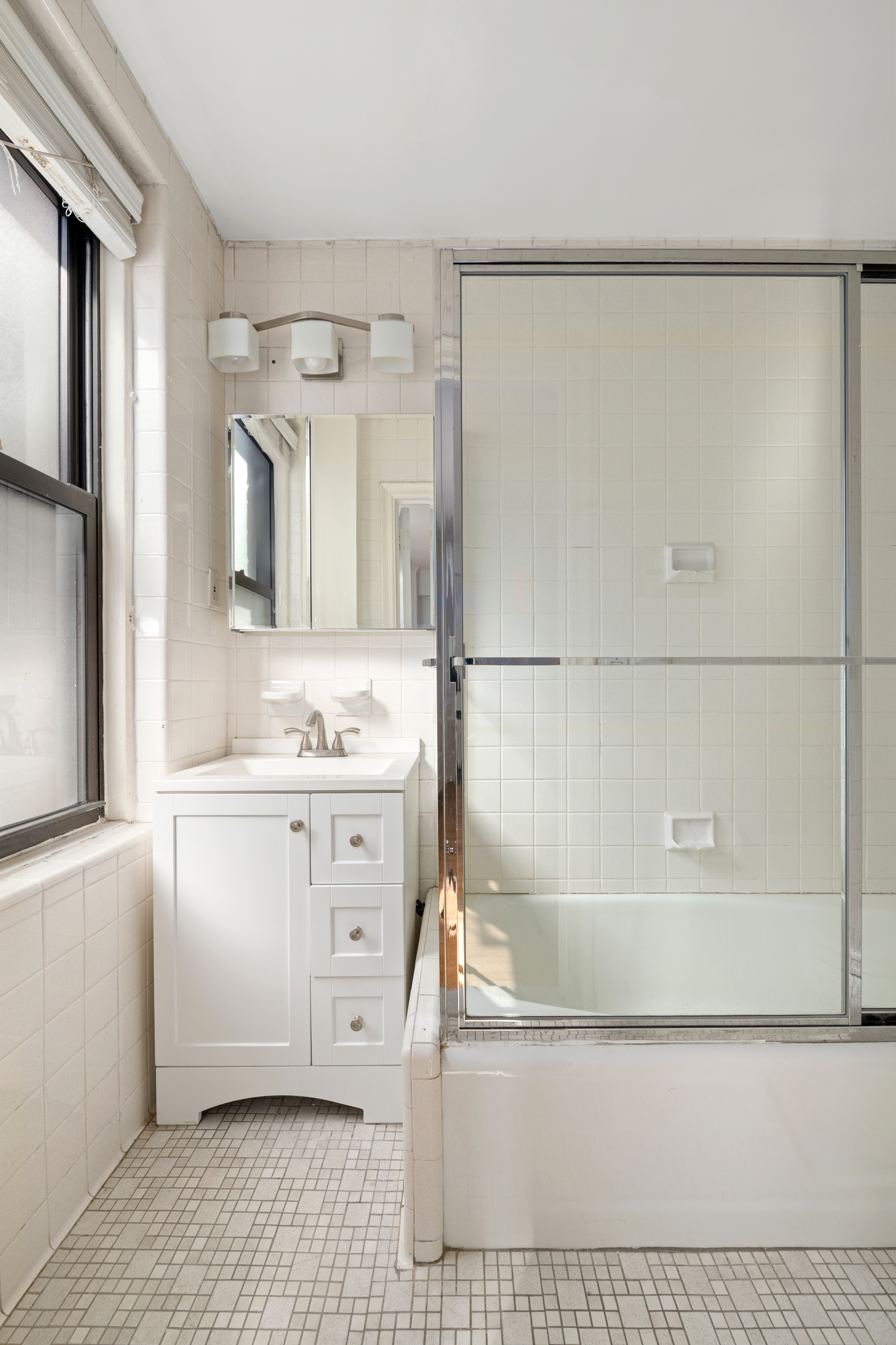 210 East 73rd Street, Unit 9EF Manhattan, NY 10021 - Photo 8 of 16 a bathroom with a granite countertop sink a mirror and a bathtub
