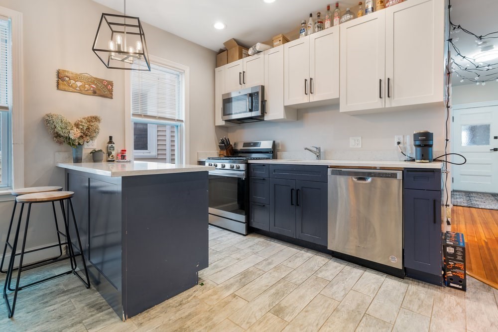 24 Buttonwood Street Boston, MA 02125 - Photo 24 of 43 a kitchen with stainless steel appliances granite countertop a stove a sink dishwasher and a microwave oven with cabinets