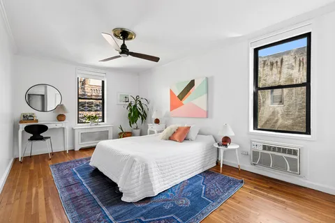 a bedroom with a bed a dresser and next to a window