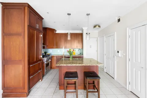 a kitchen with granite countertop a refrigerator and a stove top oven