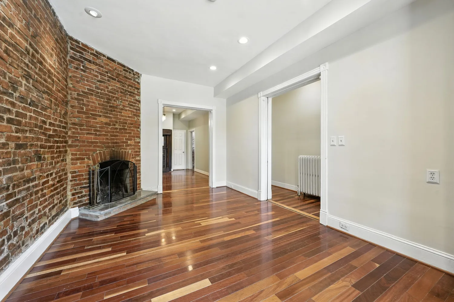 a view of a livingroom with wooden floor and a fireplace