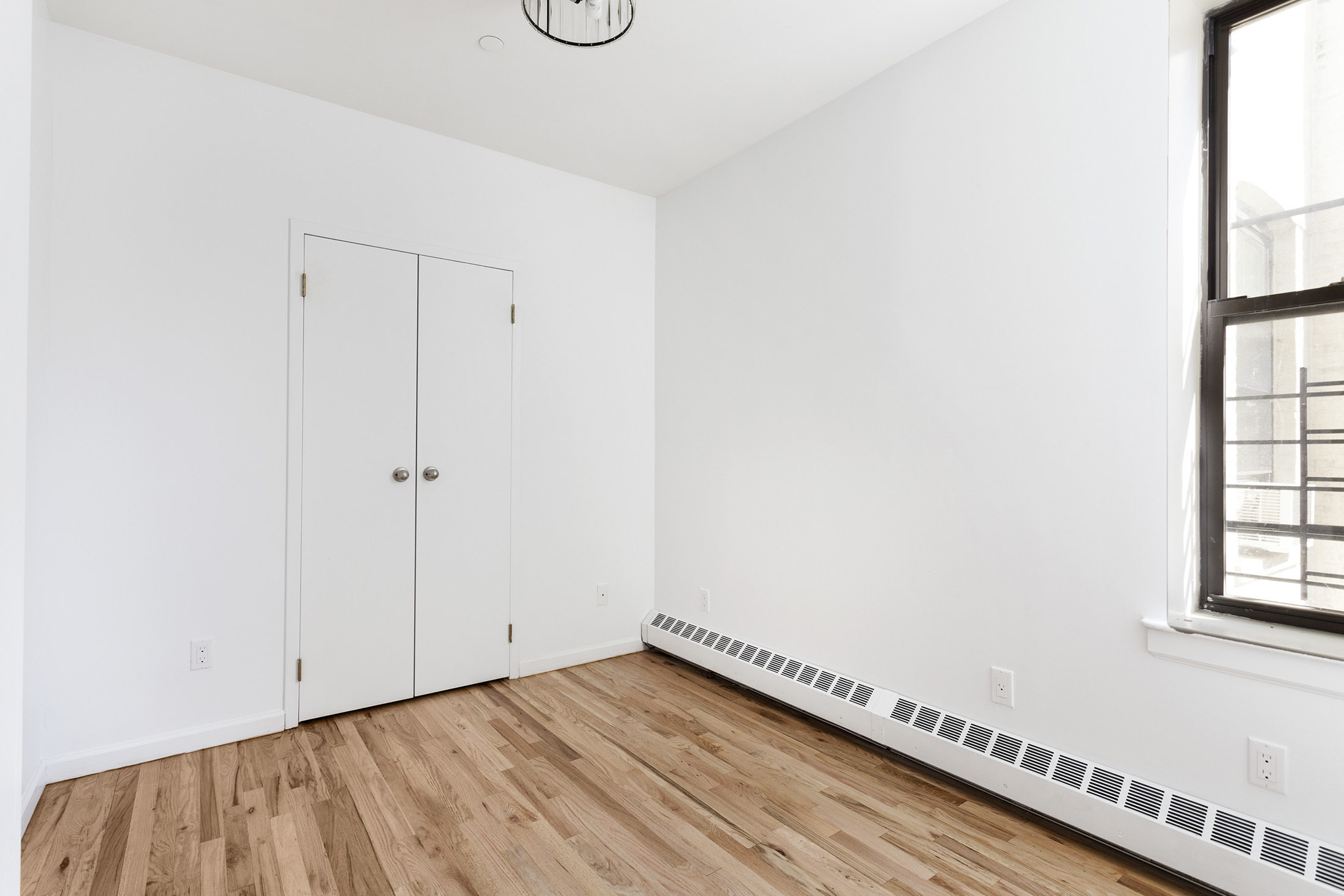 660 St Nicholas Avenue, Unit 63 Manhattan, NY 10030 - Photo 6 of 14 a view of an empty room with wooden floor and a window