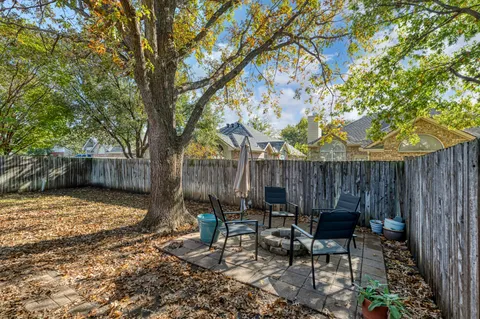 a view of backyard with table and chairs and a large tree